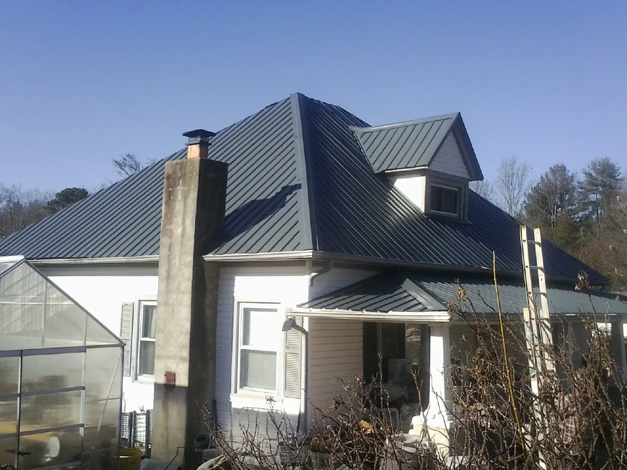 Dark blue standing seam metal roof on a white farmhouse with dormer — Slate & Tile Roof Repair by Roofing Brothers in Napa