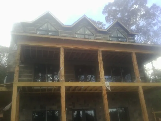 Dormers and porch framing on a large log home under construction — Roof Coating work by our crew in Napa